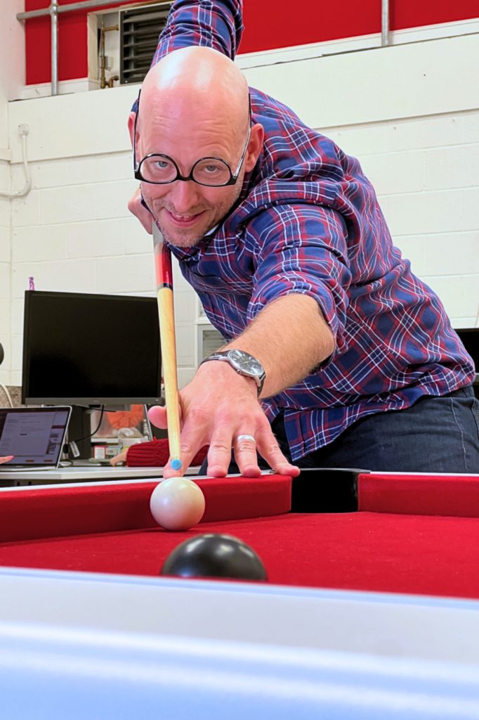 Pete playing pool with upside down glasses on his face