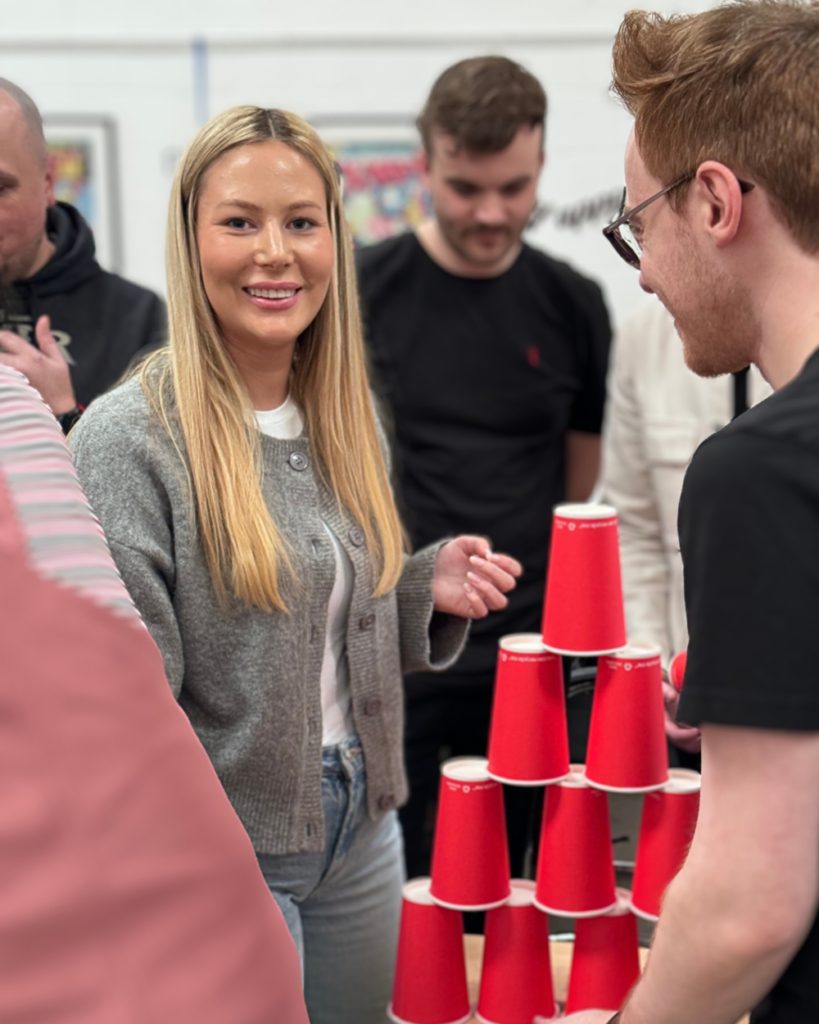 Rebecca smiling while playing cup game with team